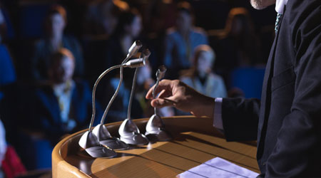 a podium with microphones and someone about to speak into them